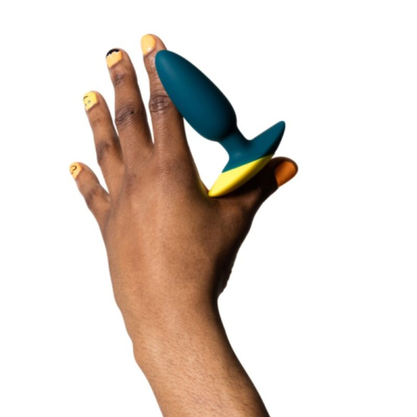 Mano sosteniendo plug anal verde y amarillo